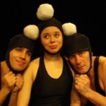 Three performers of Galumpha are shown here with silly grins and balls on their heads.